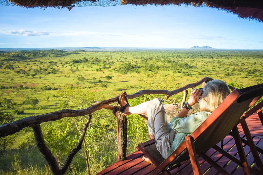 Guest relaxing at a lodge balcony, admiring stunning landscapes, Adventure Awaits: Experience a Budget Tanzania Safari with PAG Safaris for unforgettable views